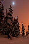 The moon showing through the mostly overcast sky at sunset in the Cascade Mountains.